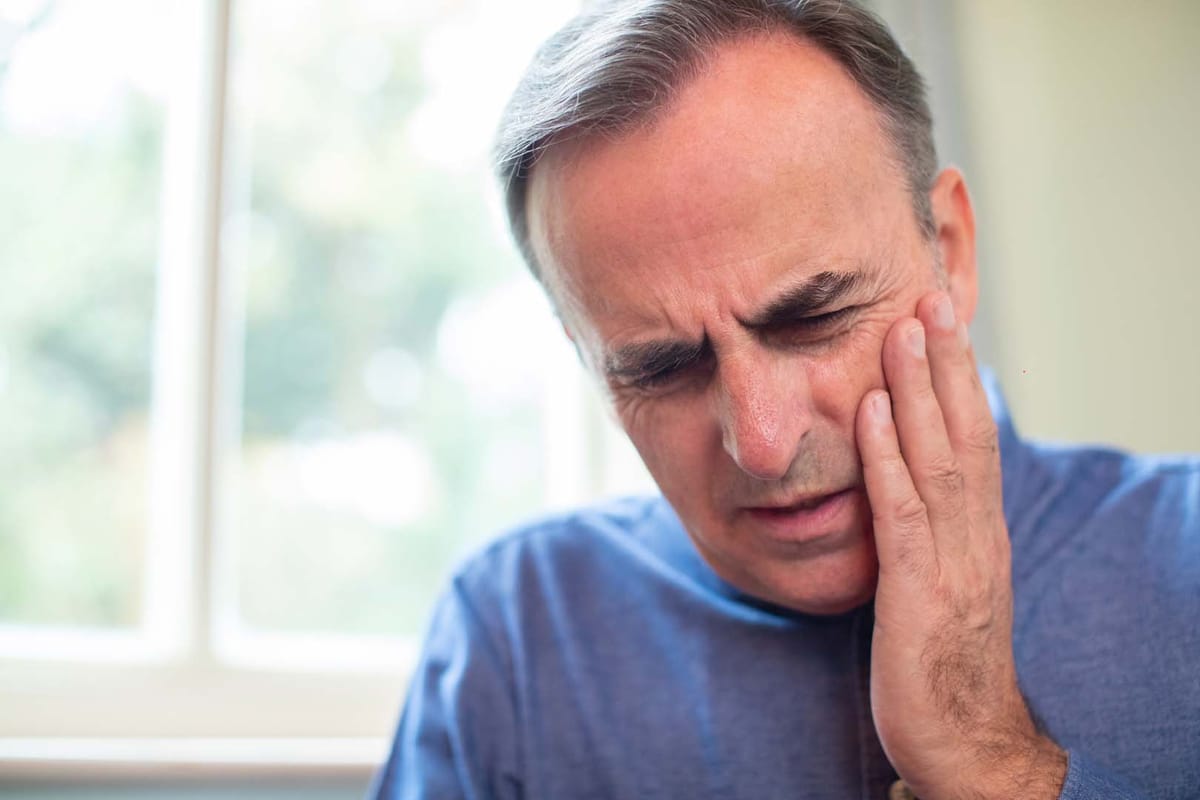 A patient holding the side of their jaw in pain