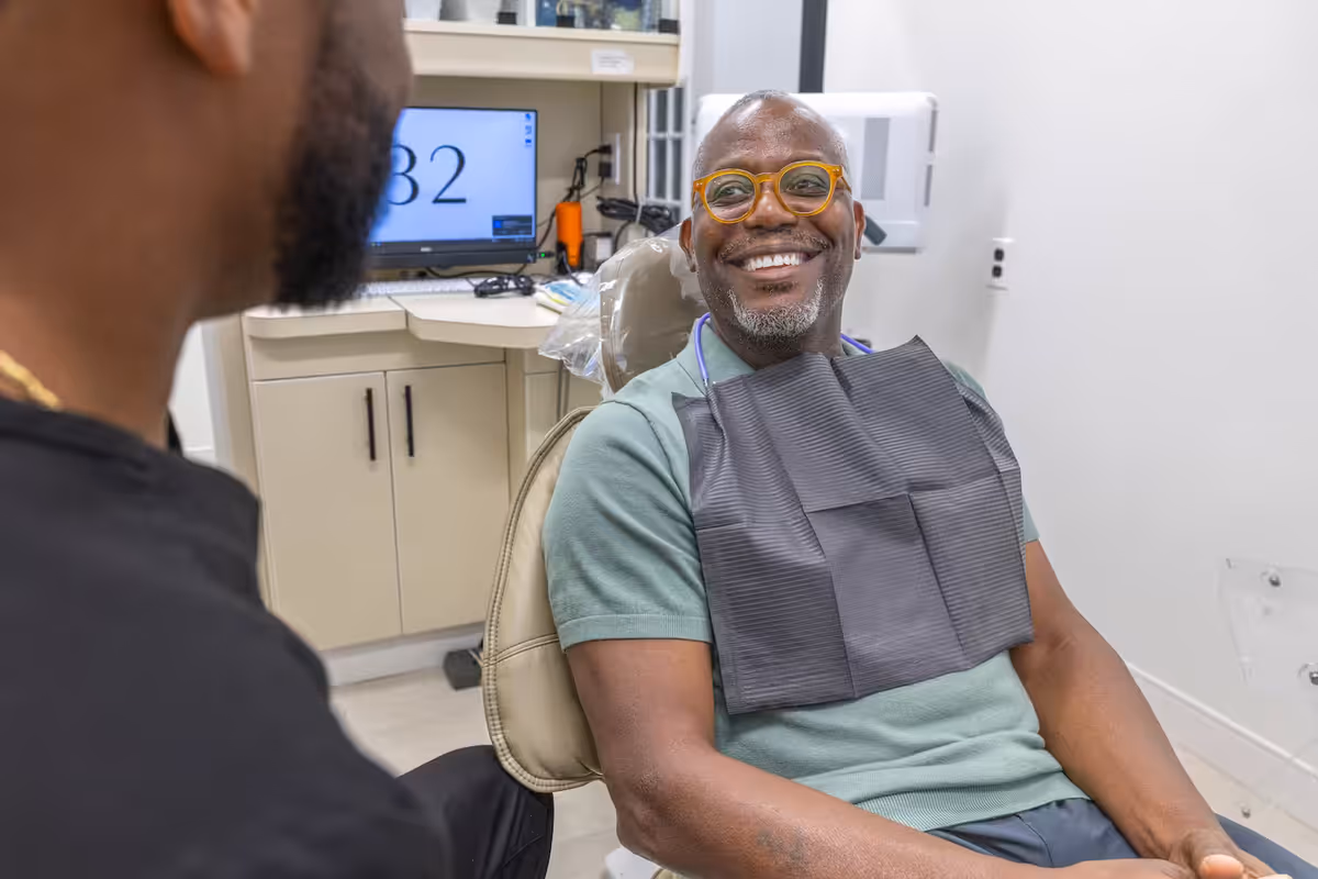 A smiling patient in the chair during a dental exam with Dr. Charles White