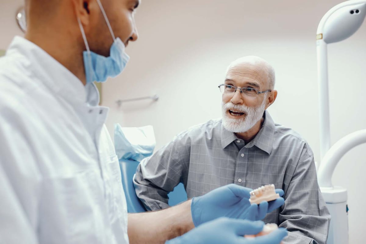 A clinician showing a patient a full-arch implant prosthesis
